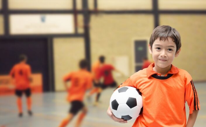 menino com bola de futebol ilustra a importância dos esportes para crianças