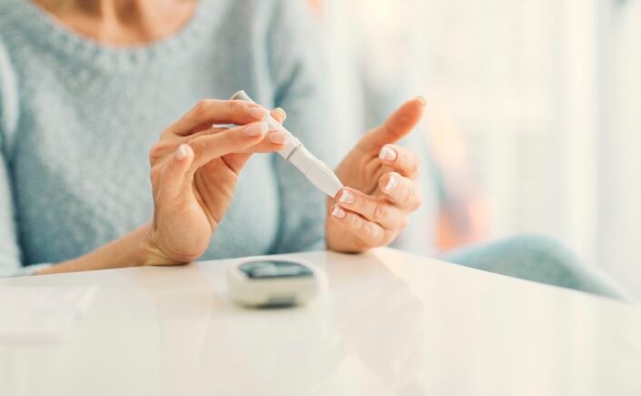 mulher medindo glicose e alertando os sintomas do diabetes