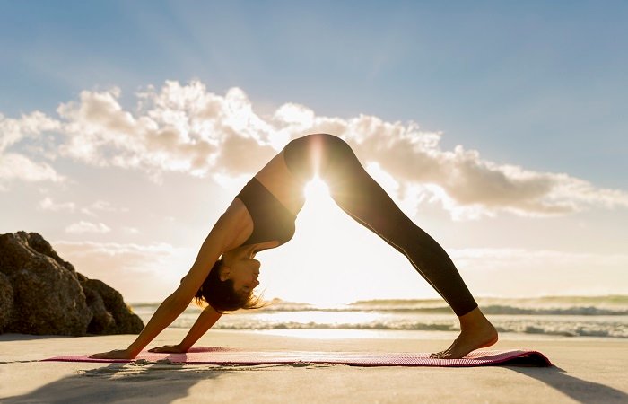 pessoa praticando yoga na praia